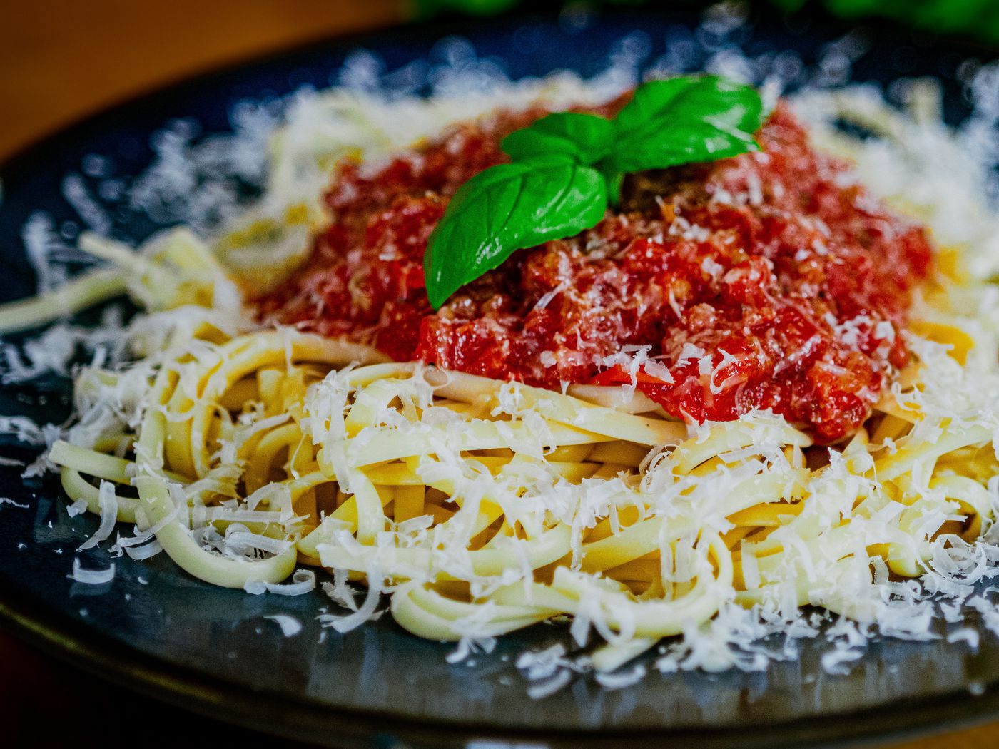 Teller Pasta mit Tomatensauce, geriebenem Käse und frischem Basilikum