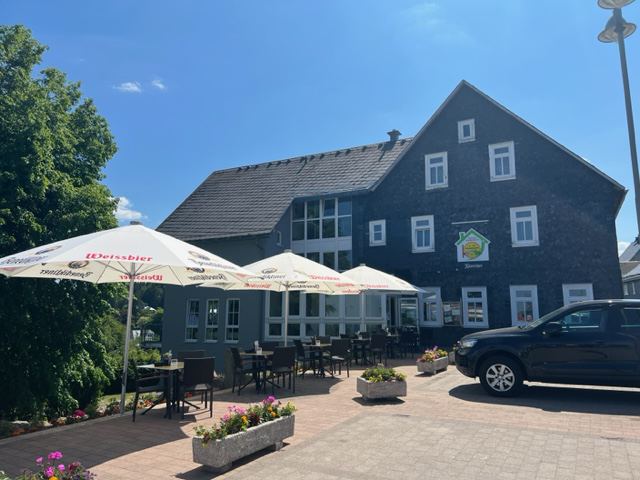 Das Haus der Pizzaheros und der Pension Breitenborn in der Hauptstraße mit Sonnenschirmen davor